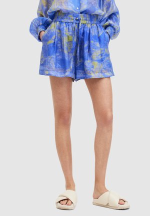 Blå mønstrede shorts lavet af letvægtsstof med elastisk talje og sidelommer, parret med cremede slidesandaler.