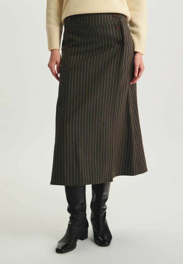Jupe midi rayée brune en tissu texturé, avec une fermeture à boutons sur le côté et une taille haute. Portée avec des bottes noires jusqu'aux genoux.