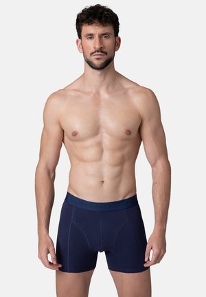 Granatowe bokserki z miękkim elastycznym paskiem w talii, z subtelnym logo. Materiał wydaje się gładki i dopasowany.