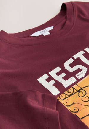 Tricou din bumbac burgund cu un print mare alb "FEST" și un design colorat cu un model de friză decorativă în partea de jos.
