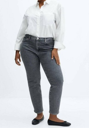 Vaqueros de mezclilla gris con un corte slim, que presentan una cintura de altura media y un diseño clásico de cinco bolsillos. Combinados con una camisa blanca de botones.
