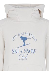 Felpa crema con collo alto. Presenta una grafica blu con la scritta "È uno stile di vita Ski & Snow Club", accompagnata da un'illustrazione di uno sciatore.