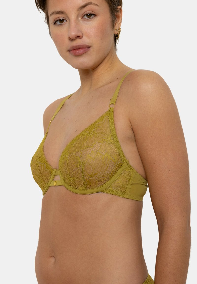 Soutien-gorge triangle en dentelle verte avec des bretelles ajustables, un motif floral et un fermoir central. Fabriqué en matériau doux avec une texture lisse.