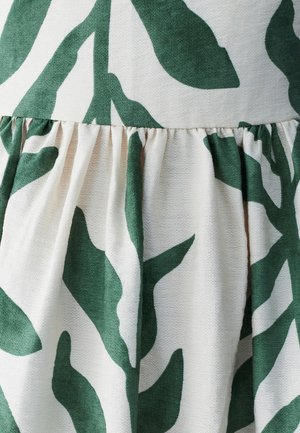 Floral-patterned fabric featuring large green leaves on a cream background. Textured material with gathered detailing along the hem.