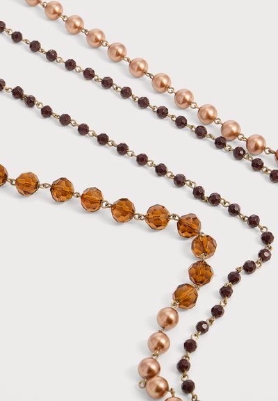 Trois colliers de perles disposés en diagonale, présentant de grosses perles rondes en cuivre, de petites perles brun foncé facettées et des perles d'ambre facettées de taille moyenne, reliées par des anneaux dorés.
