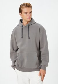 Gray pullover hoodie made of soft fabric, featuring a front kangaroo pocket, adjustable drawstring hood, and ribbed cuffs and hem.