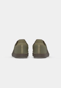 Green mesh sneakers with suede accents, textured panels, and a brown rubber sole; features a padded collar and contrasting stitching.