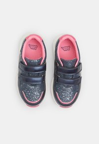 Sötétkék felsőrészű sneaker, mely pöttyös mintával, rózsaszín kiegészítőkkel és dupla állítható tépőzárral rendelkezik; könnyű, fehér talppal.