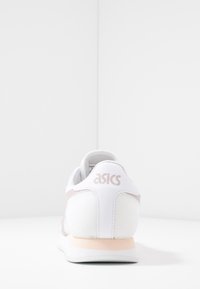 Vit mesh löparsko med ljusrosa detaljer. Har en vadderad krage, märkesklack och en strukturerad sula för bättre grepp.