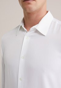 Biela košeľa na gombíky s hladkým povrchom, klasickým golierom a dvoma gombíkmi viditeľnými vpredu. Čistý, minimalistický dizajn.