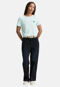 T-shirt rayé bleu clair et blanc à manches courtes avec un graphique de soleil, assorti à un jean foncé taille haute et des baskets blanches.
