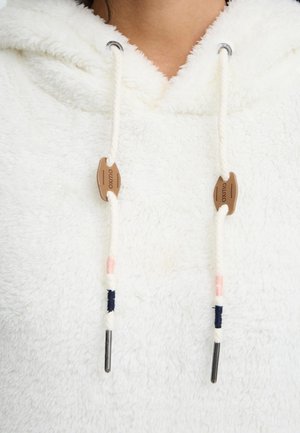 Hvit fleece hettegenser med en teksturert overflate. Snorene har en naturlig treperle og metallender, akkompagnert av lyserosa og mørkeblå tråder.