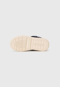 Geox sneaker talpája, bézs gumi, textúrázott mintázattal és szellőzőlyukakkal. Oldalán megjelenik a domború 'Geox' logó.