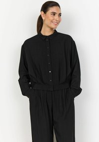 Camicia nera con bottoni, colletto, maniche lunghe e vestibilità morbida; realizzata in tessuto leggero con una texture liscia e un design minimale.
