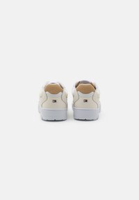 Zapatillas blancas con parte superior de cuero y malla, que cuentan con un talón acolchado, suela de goma gris y un pequeño logotipo en el costado.