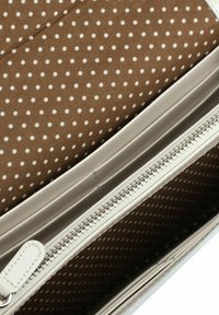 Bruin interieur met witte polka dots, voorzien van meerdere lades voor kaarten en een witte rits met leren trekkoord. Gladde, synthetische buitenkant.