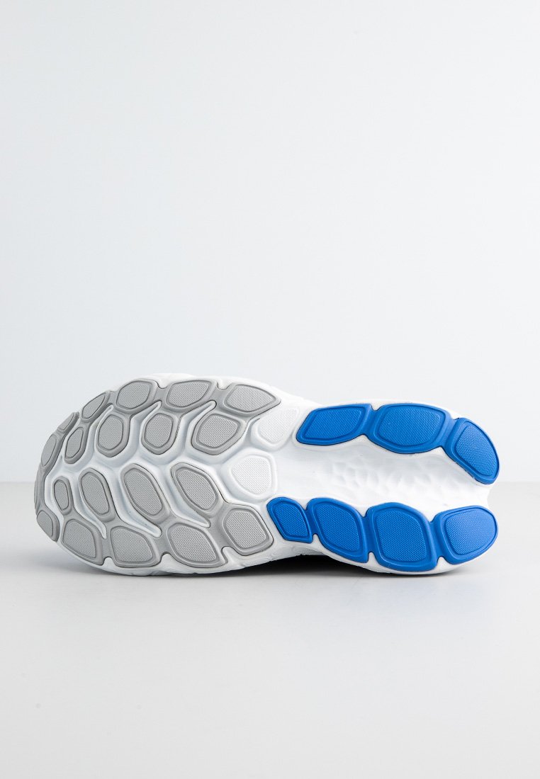 Suela de zapatilla deportiva blanca con un patrón texturizado. Presenta secciones de goma gris y acentos azules. Diseño redondeado y ergonómico para un mejor soporte.