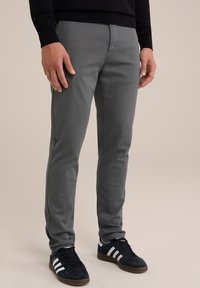 Pantaloni slabi gri, dintr-un amestec de bumbac, cu o textură netedă, buzunare standard și purtați cu teniși negri.