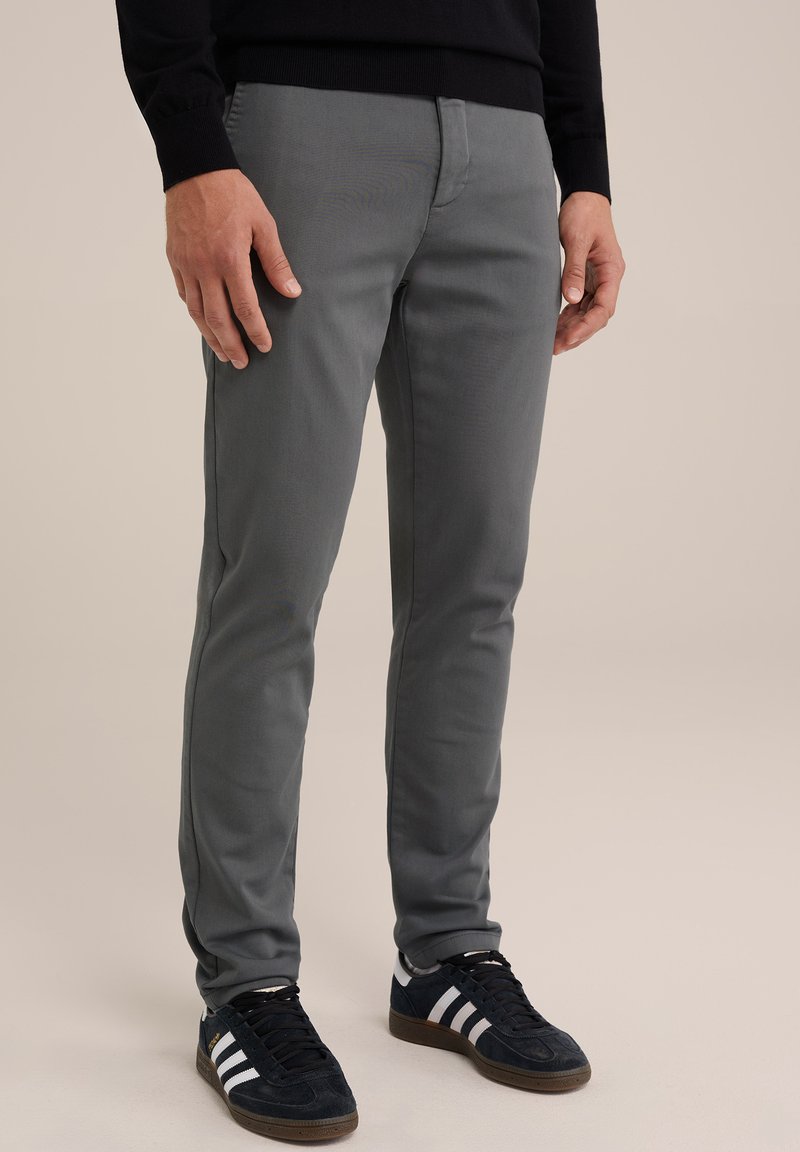 Pantaloni slabi gri, dintr-un amestec de bumbac, cu o textură netedă, buzunare standard și purtați cu teniși negri.