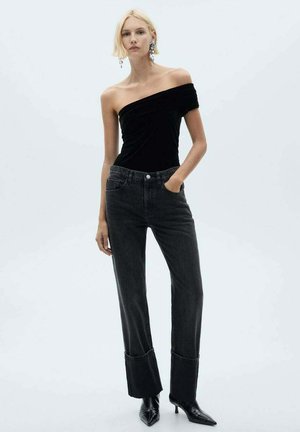 Black off-the-shoulder velvet top paired with high-waisted, dark wash jeans featuring flared cuffs and ankle-length cut.
