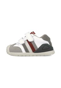 Zapatilla gris y blanca con correas de velcro, que presenta rayas rojas y grises, acentos de gamuza texturizada y una suela de goma con un patrón de agarre.