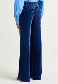 Pantaloni a gamba larga in velluto blu navy con vita arricciata, dotati di tasche anteriori e design con cuciture aperte per una vestibilità comoda.