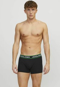 Boxers noirs avec une ceinture verte et blanche portant le texte "JACK & JONES." Fabriqués en tissu doux avec un design ajusté.