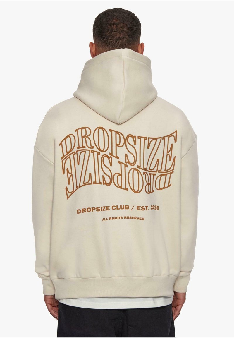 Beige hettegenser med stort, buet tekst som sier "DROPSIZE" i brunt, med «DROPSIZE CLUB / EST. 2020» under. Myk stoff, avslappet passform.