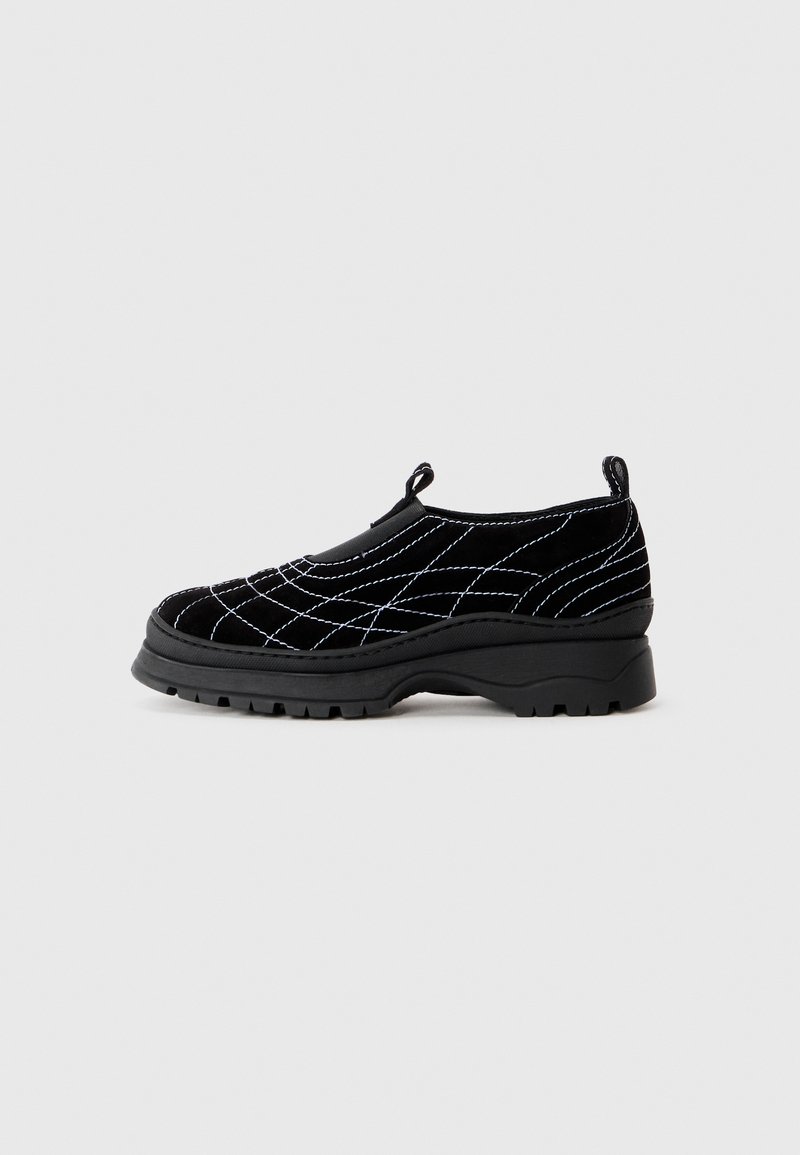 Fekete, bársonyból készült slip-on cipő, fehér tűzött gyémántmintával, kerek orral és vastag gumitalppal. A sarkán húzófül található.