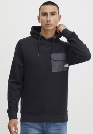 Navy hoodie with gray chest pocket, drawstring hood, and ribbed cuffs. Made of soft fabric, featuring a subtle texture and logo detail.