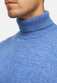 Blauer gestrickter Rollkragenpullover mit strukturierter Oberfläche und geripptem Kragen, der einen glatten, leichten Stoff präsentiert.