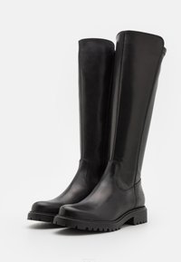 Bottes en cuir noir hauteur genou avec une finition lisse, bout rond, semelle en caoutchouc et détail de fermeture éclair sur le côté. Le motif de semelle rugueuse améliore l'adhérence.