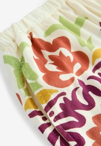 Tessuto con motivo floreale in diversi colori tra cui arancione, verde, viola e giallo, caratterizzato da una texture morbida e un elastico in vita.