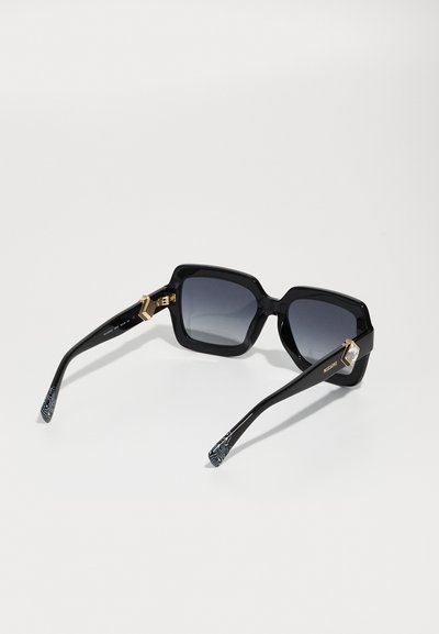 Mustad mustad prillid halli gradient läätsedega, läikivad mustad käed, kuldsed riistvara aktsendid ja tekstuuriga mustriga otsad.