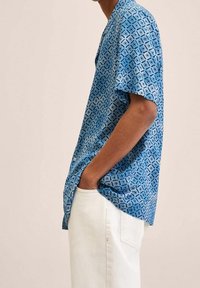 Korte mouwen shirt in het blauw met een geometrisch patroon, gemaakt van lichtgewicht materiaal. Bevat een klassieke kraag en knopen.