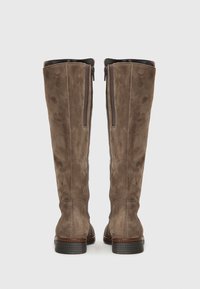 Botas de ante marrón hasta la rodilla con un acabado suave, que cuentan con una cremallera lateral y suela de goma texturizada. Detalle de cuero en el borde superior.