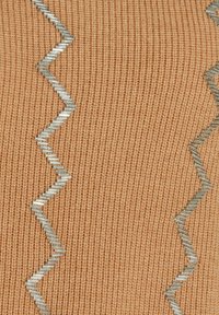 Gebreide stof in lichtoranje met een gestructureerd oppervlak, met een zigzag zilverkleurige metallic accent dat door het midden loopt.