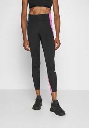 Schwarze Leggings mit pinken und blauen Seitenstreifen, hoher Bund, figurschmeichelndes Design, aus dehnbarem Material, mit einem Adidas-Logo.