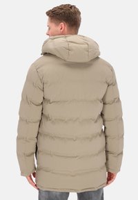 Beige puffer-takki, jossa vaakasuorat tikkausviivat, huppu ja puolipitkä malli. Sileä pinta, pehmeä kangas, eikä näkyviä metalliosia.