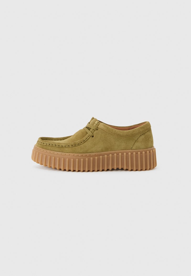 Des chaussures vertes en daim à enfiler avec une semelle en caoutchouc marron épaisse et texturée. Présente un design cousu et peu de détails sur la tige.