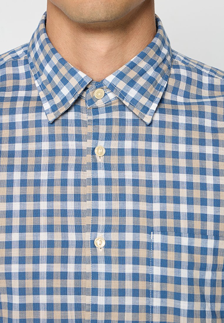 Blauwe en beige geruite shirt met een button-down kraag, knoopsluiting aan de voorkant en een zak. De stof lijkt textuur te hebben met een lichte katoenen afwerking.