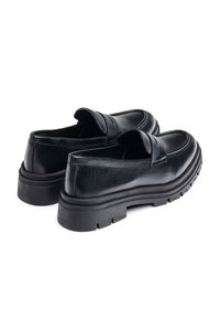 Mocasines de cuero negro con un diseño de corte bajo, que cuentan con una suela de goma gruesa y detalles de costura en la parte superior.