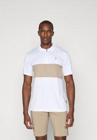 Kortermet polo-shirt i hvit med en beige horisontal stripe. Har en kvart-glidelås foran og en liten logo på brystet.
