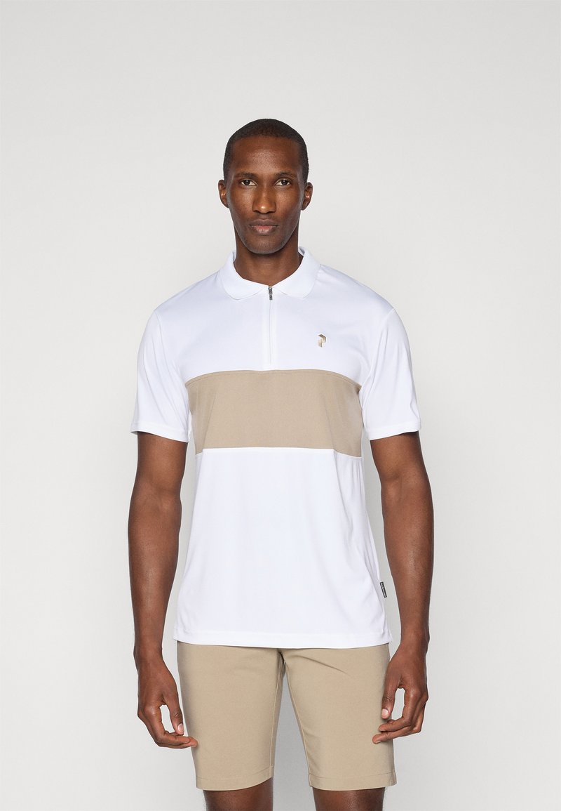 Kortermet polo-shirt i hvit med en beige horisontal stripe. Har en kvart-glidelås foran og en liten logo på brystet.