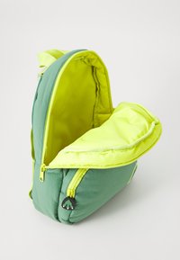 Green and yellow backpack made of soft fabric, featuring a zippered main compartment and a rounded top, with a small logo detail.