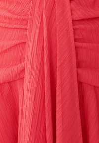 Koralfarbenes Textil mit vertikalen Falten und einem leicht schimmernden Finish. Leicht und fließendes Design, das sich für Bekleidung eignet.
