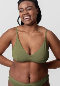Olive green, seamless bralette with thin adjustable straps and a deep V-neckline. Textured skin visible on midsection.