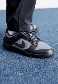 Črne in sive Nike superge imajo gladek usnjen kapico za prste, mrežaste panele in teksturirano podplat z značilnim logotipom swoosh.