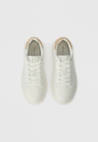 Ζευγάρι λευκών χαμηλών αθλητικών παπουτσιών με λευκές κορδόνες και καφέ λεπτομέρειες στη φτέρνα, απεικονιζόμενο από πάνω σε απλή ανοιχτόχρωμη βάση.