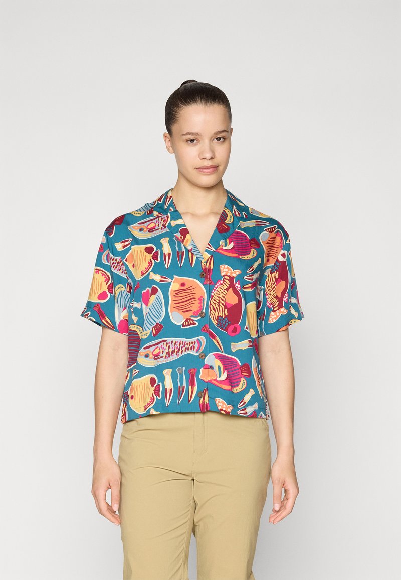 Camicia a maniche corte con bottoni in tessuto teal, decorata con un motivo di pesci colorati, con varie forme di pesci in rosa, giallo e blu.